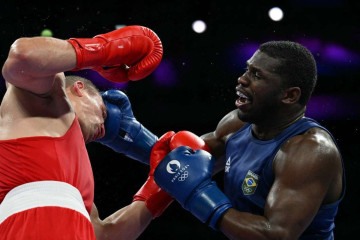 O ucraniano Oleksandr Khyzhniak (de vermelho) luta contra o brasileiro Wanderley De Souza Pereira (de azul) na luta de boxe masculino até 80kg nas quartas de final durante os Jogos Olímpicos de Paris 2024 -  (crédito:  AFP)