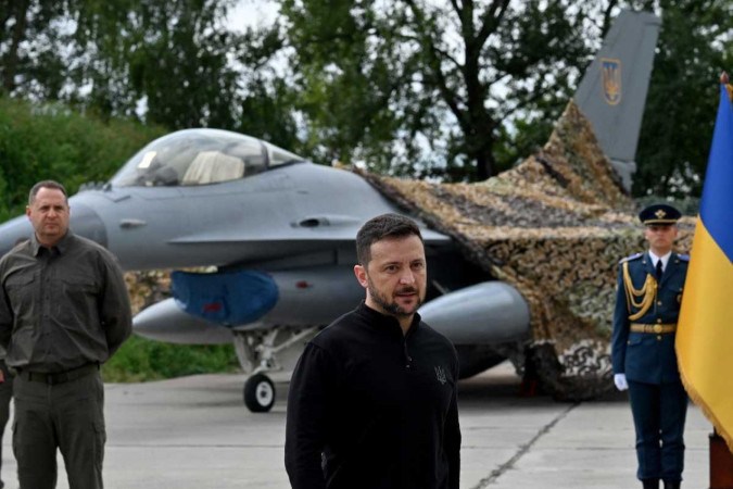 Presidente da Ucrânia, Volodymyr Zelensky (C), em frente a um caça F16 durante uma cerimônia realizada para marcar o Dia das Forças Aéreas Ucranianas em um local não revelado -  (crédito: Sergei Supinsky/AFP)