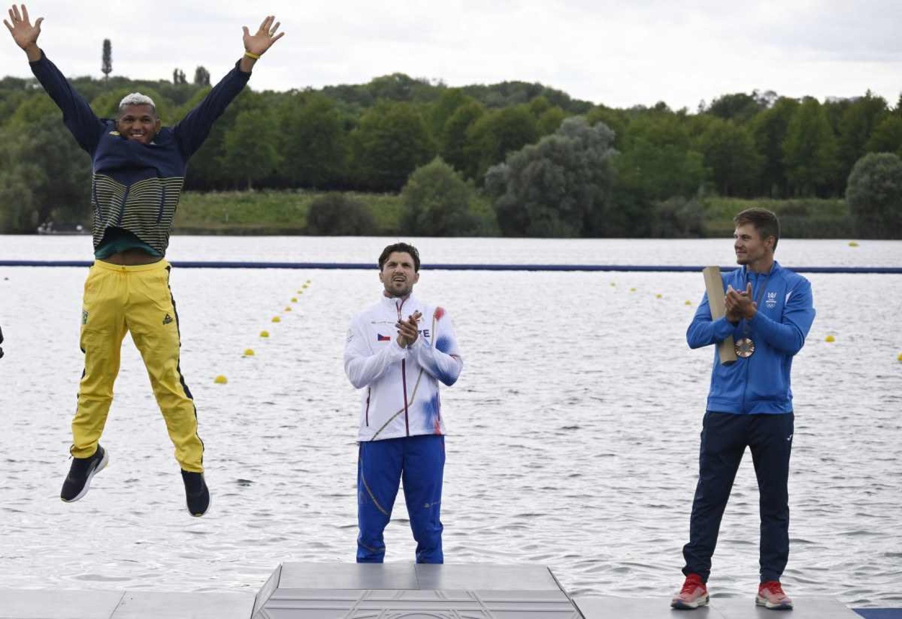 (Da esquerda para a direita) O medalhista de prata do Brasil Isaquias Guimarães Queiroz, o medalhista de ouro da República Tcheca Martin Fuksa e o medalhista de bronze da Moldávia Serghei Tarnovschi comemoram no pódio durante a cerimônia de medalhas após a final dos 1000 m de canoagem individual masculina da competição de canoagem velocidade no Estádio Náutico de Vaires-sur-Marne em Vaires-sur-Marne durante os Jogos Olímpicos de Paris 2024, em 9 de agosto de 2024.      