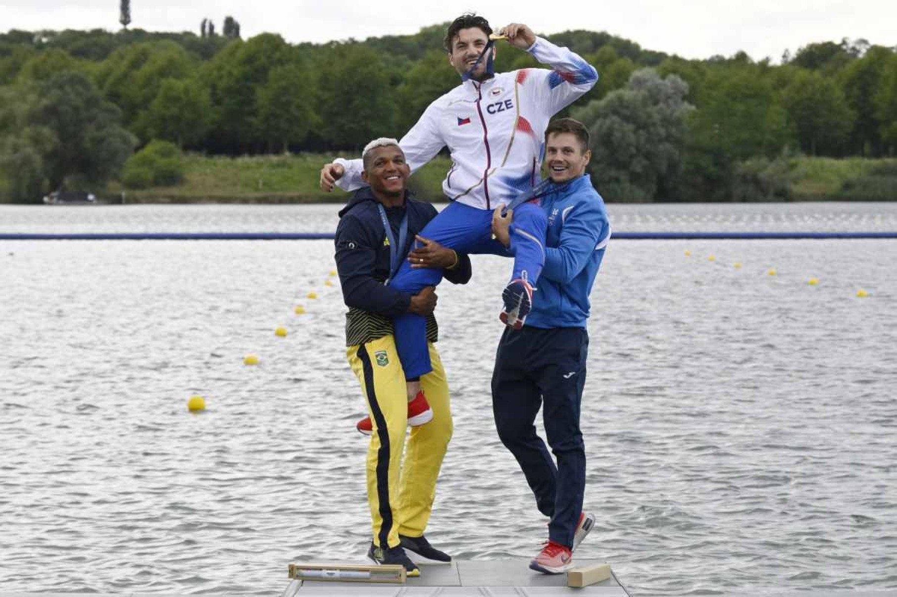 (Da esquerda para a direita) O medalhista de prata do Brasil Isaquias Guimarães Queiroz, o medalhista de ouro da República Tcheca Martin Fuksa e o medalhista de bronze da Moldávia Serghei Tarnovschi comemoram no pódio durante a cerimônia de medalhas após a final dos 1000 m de canoagem individual masculina da competição de canoagem velocidade no Estádio Náutico de Vaires-sur-Marne em Vaires-sur-Marne durante os Jogos Olímpicos de Paris 2024, em 9 de agosto de 2024.      