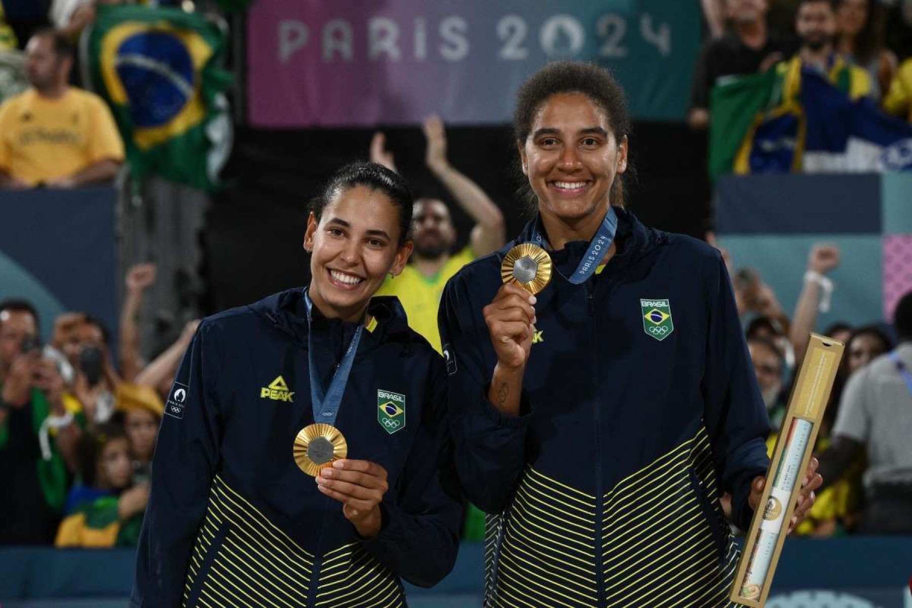 As medalhistas de ouro Eduarda Santos Lisboa (E) e a brasileira Ana Patrícia Silva Ramos posam com suas medalhas no pódio para a cerimônia de vitória do evento de vôlei de praia feminino durante os Jogos Olímpicos de Paris 2024, no Estádio da Torre Eiffel, em Paris, em 9 de agosto de 2024. 