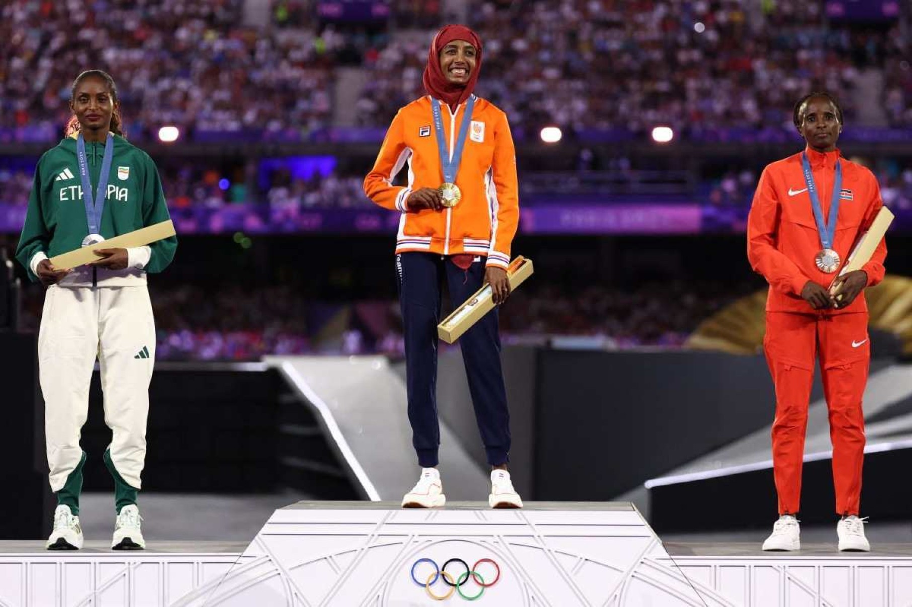 (Da esquerda para a direita) Tigst Assefa, da Etipia, medalhista de prata, Sifan Hassan, da Holanda, medalhista de ouro, e Hellen Obiri, do Qunia, medalhista de bronze, posam durante a cerimnia do pdio da maratona feminina do evento de atletismo durante a cerimnia de encerramento dos Jogos Olmpicos de Paris 2024, no Stade de France, em Saint-Denis, nos arredores de Paris, em 11 de agosto de 2024.      