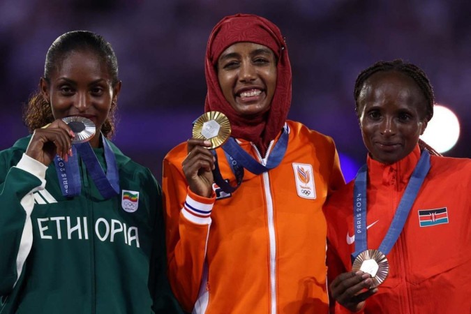 (Da esquerda para a direita) Tigst Assefa, da Etiópia, medalhista de prata, Sifan Hassan, da Holanda, medalhista de ouro, e Hellen Obiri, do Quênia, medalhista de bronze, posam durante a cerimônia do pódio da maratona feminina do evento de atletismo durante a cerimônia de encerramento dos Jogos Olímpicos de Paris 2024, no Stade de France, em Saint-Denis, nos arredores de Paris, em 11 de agosto de 2024.       -  (crédito: Franck FIFE / AFP)