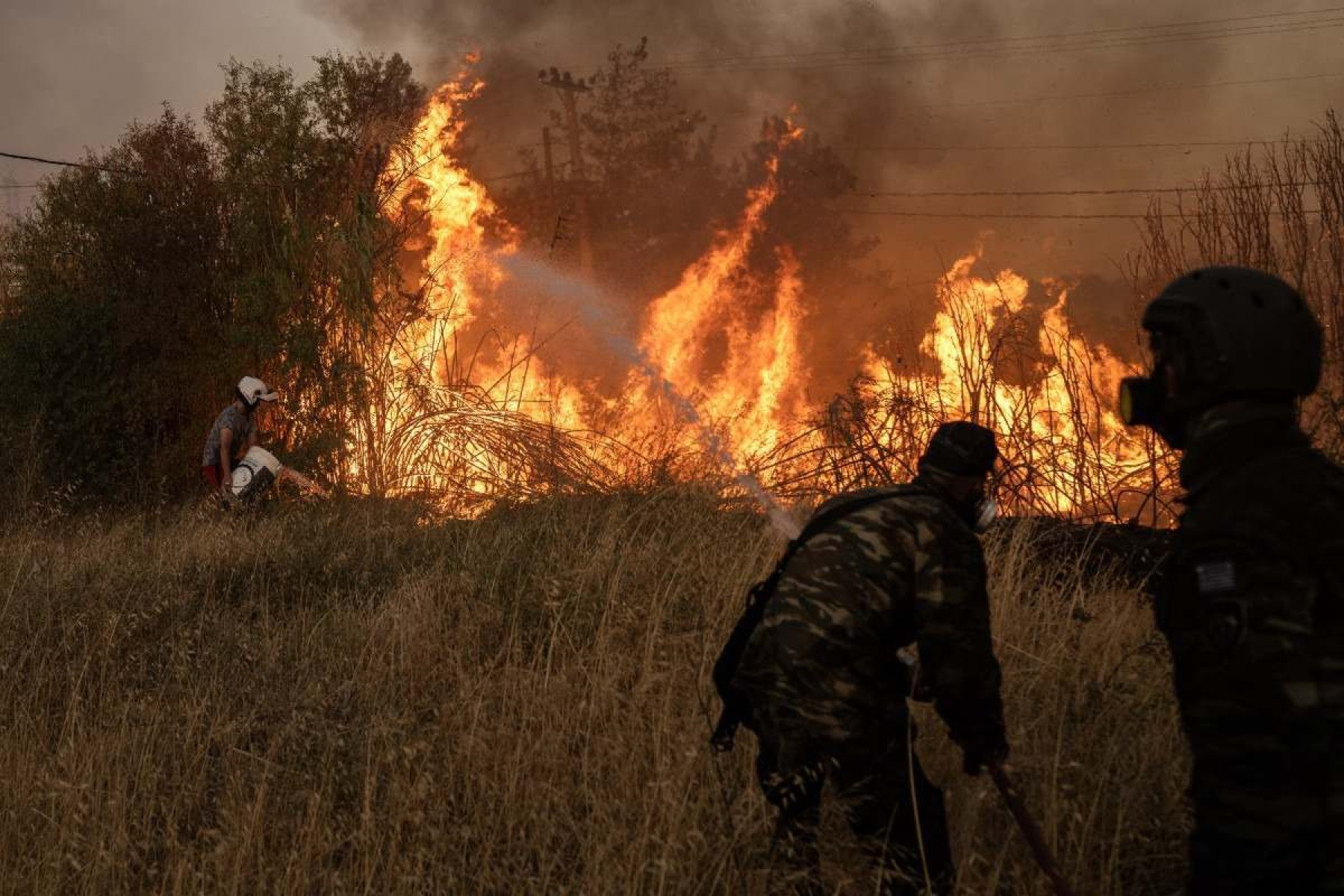  Volunteers try to extinguish a wildfire near Penteli, on August 12, 2024. Greeces civil protection authorities ordered the evacuation of several towns in the north-eastern suburbs of Athens, threatened by a violent fire that started the day before and is spreading. European Union said that four countries -- Italy, France, the Czech Republic and Romania -- would send assistance at the request of Greece which is combating a massive wildfire burning through Athens suburbs. (Photo by Angelos TZORTZINIS / AFP)       