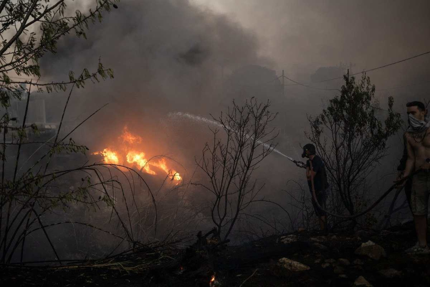  Volunteers try to extinguish a wildfire near Penteli, on August 12, 2024. Greeces civil protection authorities ordered the evacuation of several towns in the north-eastern suburbs of Athens, threatened by a violent fire that started the day before and is spreading. European Union said that four countries -- Italy, France, the Czech Republic and Romania -- would send assistance at the request of Greece which is combating a massive wildfire burning through Athens suburbs. (Photo by Angelos TZORTZINIS / AFP)       