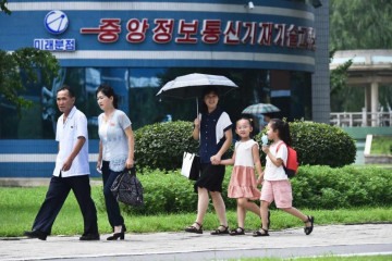       Pessoas caminham em Mirae Scientists Street durante altas temperaturas, em Pyongyang, em 13 de agosto de 2024, na Coreia do Norte. -  (crédito:  KIM Won Jin / AFP)