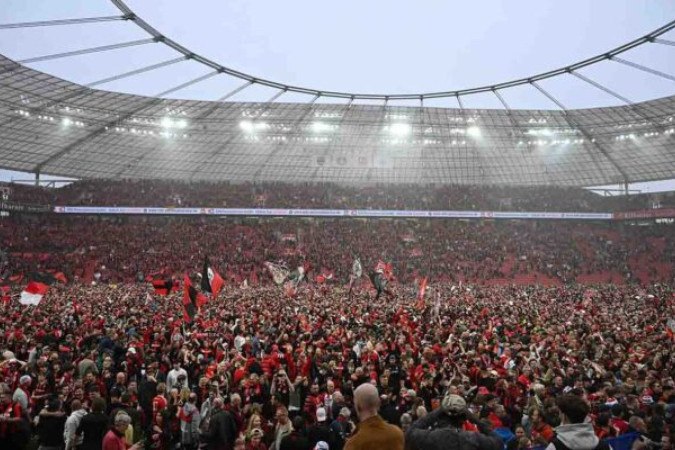  Leverkusen fans celebrate on the pitch after the German first division Bundesliga football match Bayer 04 Leverkusen v Werder Bremen in Leverkusen, western Germany, on April 14, 2024. Bayer Leverkusen were crowned 2023-24 Bundesliga champions for the first time on April 14, 2024... (Photo by INA FASSBENDER / AFP) / DFL REGULATIONS PROHIBIT ANY USE OF PHOTOGRAPHS AS IMAGE SEQUENCES AND/OR QUASI-VIDEO (Photo by INA FASSBENDER/AFP via Getty Images)
     -  (crédito:  AFP via Getty Images)