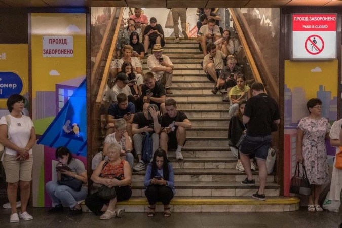 Moradores de Kiev buscam abrigo na estação de metrô Teatralna, durante bombardeio russo: canções de resistência e informações pelo celular  -  (crédito: Roman Pilipey/AFP)