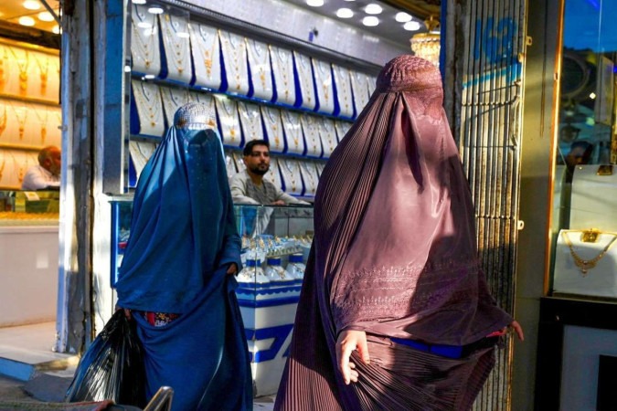     Mulheres afegãs vestidas de burca passam por joalherias em um mercado em Kandahar em 25 de agosto de 2024. (Foto de Wakil Kohsar / AFP)
      