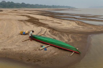     O agricultor Reis Santo Vieira, 69 anos, pinta uma canoa no leito seco do rio Madeira, na Comunidade Paraizinho, em Humaitá, Amazonas, norte do Brasil, no dia 7 de setembro de 2024. Mais de mil cidades brasileiras estão em alerta devido à baixa níveis de humidade, comparáveis ​​em alguns casos aos desertos como o Sahara, enquanto o país enfrenta a pior seca da sua história e os incêndios não param. (Foto de MICHAEL DANTAS/AFP)
      