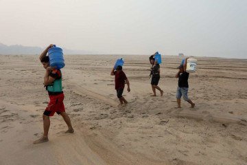  People carry drinking water along a sandbank of Madeira River in Paraizinho Community, in Humaita, Amazonas state, northern Brazil, on September 7, 2024. More than a thousand Brazilian towns are on alert due to low humidity levels, comparable in some cases to deserts like the Sahara, while the country faces the worst drought in its history and the fires do not stop. (Photo by MICHAEL DANTAS / AFP)    