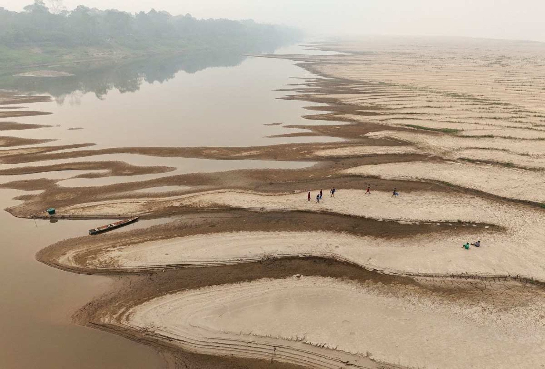 Pessoas carregam água potável ao longo de um banco de areia do Rio Madeira na Comunidade Paraizinho, em Humaitá, estado do Amazonas, norte do Brasil, em 7 de setembro de 2024      