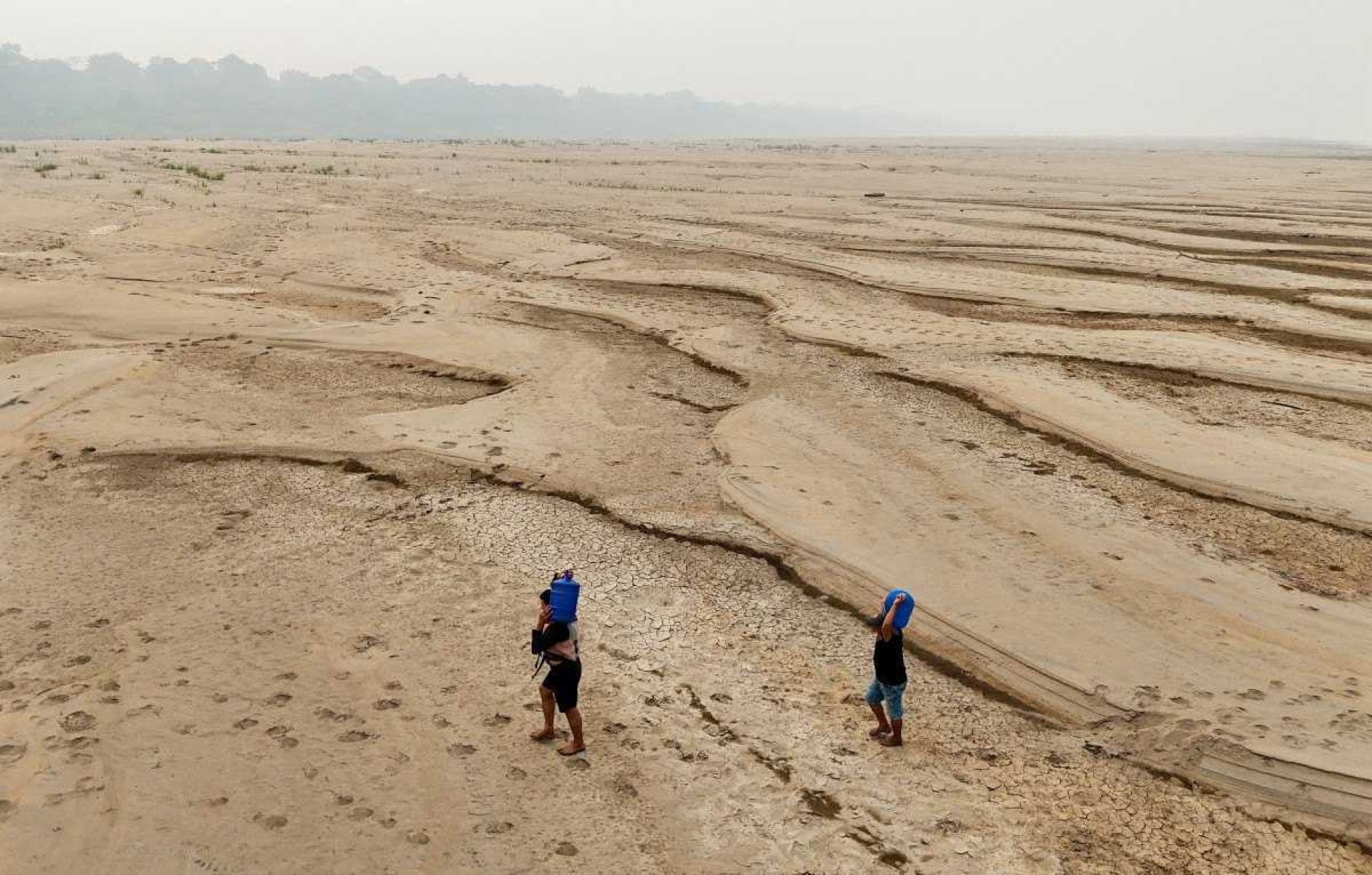 Pessoas carregam água potável ao longo de um banco de areia do Rio Madeira na Comunidade Paraizinho, em Humaitá, estado do Amazonas, norte do Brasil, em 7 de setembro de 2024      