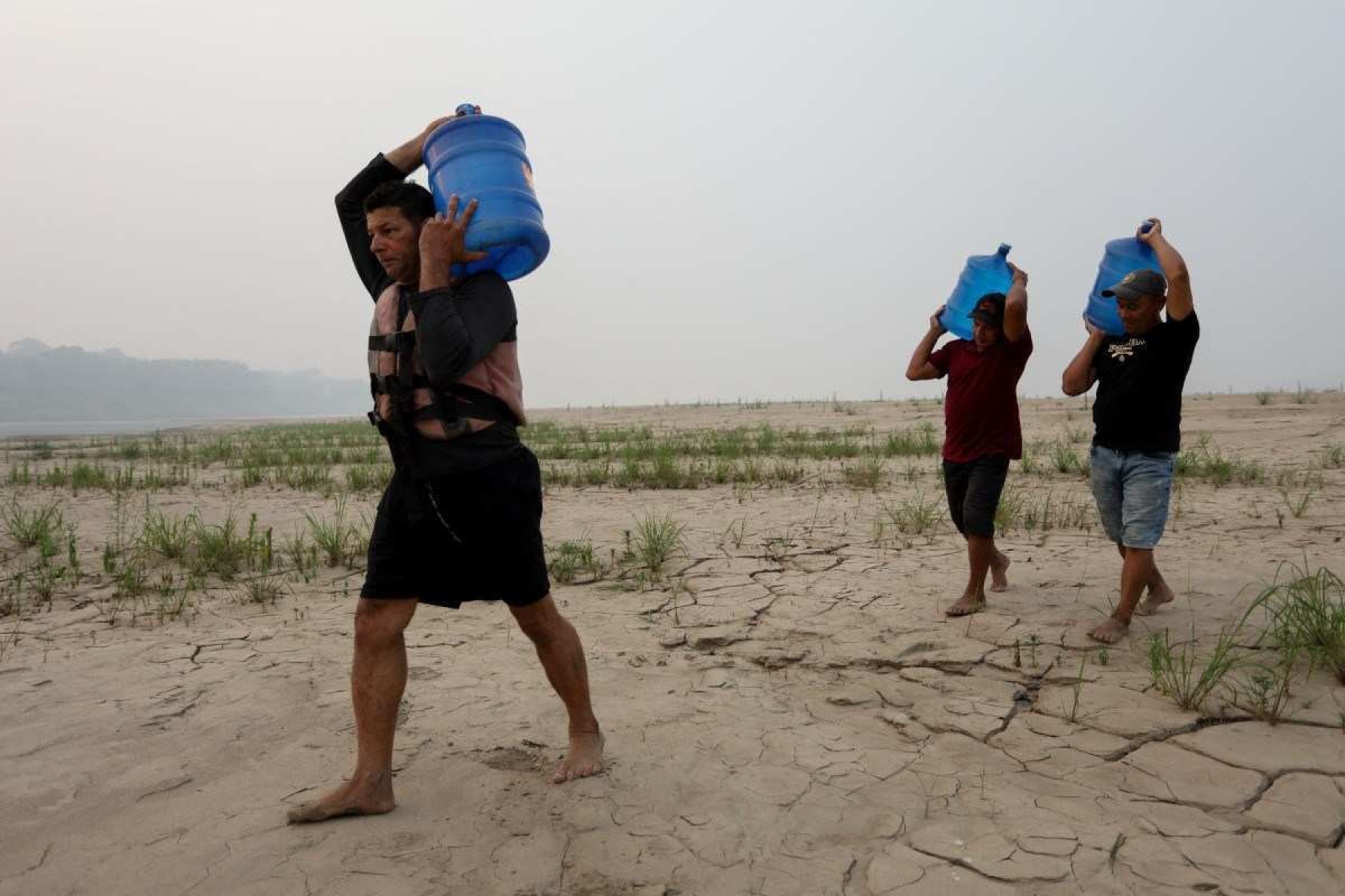 Pessoas carregam água potável ao longo de um banco de areia do Rio Madeira na Comunidade Paraizinho, em Humaitá, estado do Amazonas, norte do Brasil, em 7 de setembro de 2024      