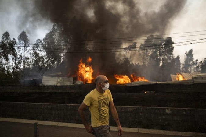 Um residente passa por um armazém em chamas durante um incêndio na aldeia de Arrancada, Águeda, em Aveiro, em 17 de setembro de 2024       -  (crédito: PATRICIA DE MELO MOREIRA / AFP)