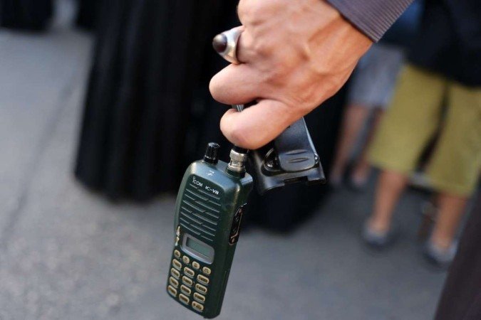 Morador de Beirute segura walkie-talkie depois de remover a bateria, durante funeral de vítimas dos ataques de terça-feira