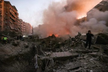 Pessoas e equipes de resgate se reúnem perto dos escombros fumegantes de um prédio destruído em um ataque aéreo israelense no bairro de Haret Hreik, nos subúrbios ao sul de Beirute, em 27 de setembro de 2024.  -  (crédito: Ibrahim AMRO / AFP)