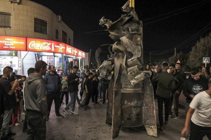 Palestinos da vila de Dura, a oeste de Habron, na Cisjordânia, reúnem-se em torno de um míssil iraniano para comemorar o ataque 