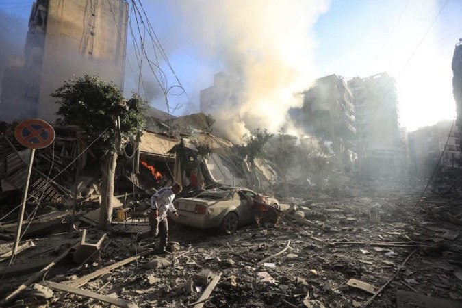 Morador de Beirute caminha sobre escombros de prédio destruído durante ataque aéreo israelense, no bairro de Moawwad (sul) -  (crédito: AFP)