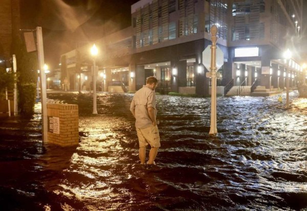 Um homem caminha através das ondas que inundam a rua depois que o furacão Milton atingiu a costa na área de Sarasota em 09 de outubro de 2024, em Fort Myers, Flórida -  (crédito: JOE RAEDLE / GETTY IMAGES NORTH AMERICA / Getty Images via AFP)