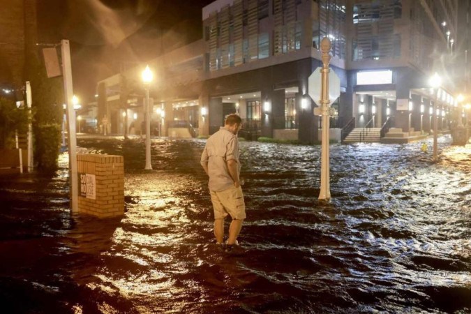 Um homem caminha através das ondas que inundam a rua depois que o furacão Milton atingiu a costa na área de Sarasota em 09 de outubro de 2024, em Fort Myers, Flórida -  (crédito: JOE RAEDLE / GETTY IMAGES NORTH AMERICA / Getty Images via AFP)