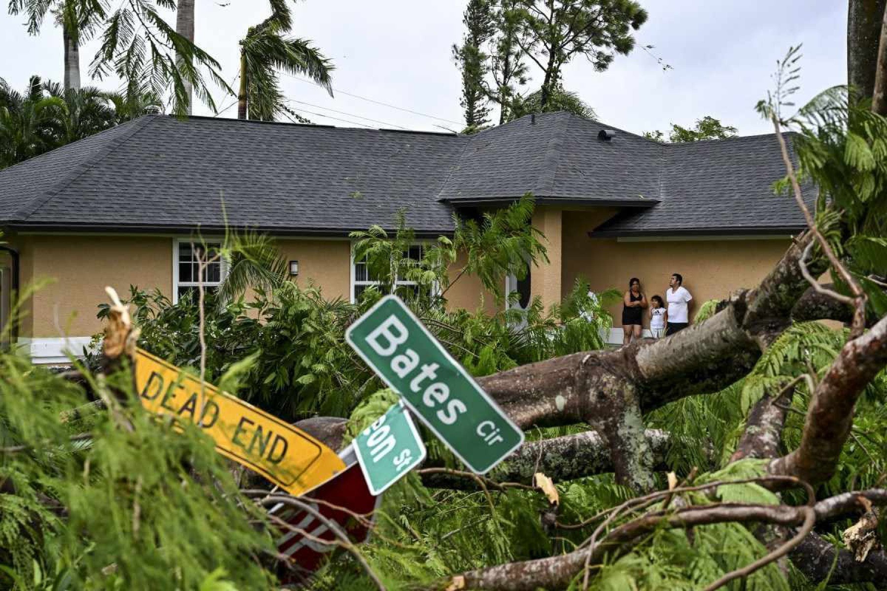 Oscar Garcia (R) com sua família está do lado de fora de sua casa após ser atingido por um tornado em Fort Myers, Flórida, em 9 de outubro de 2024 