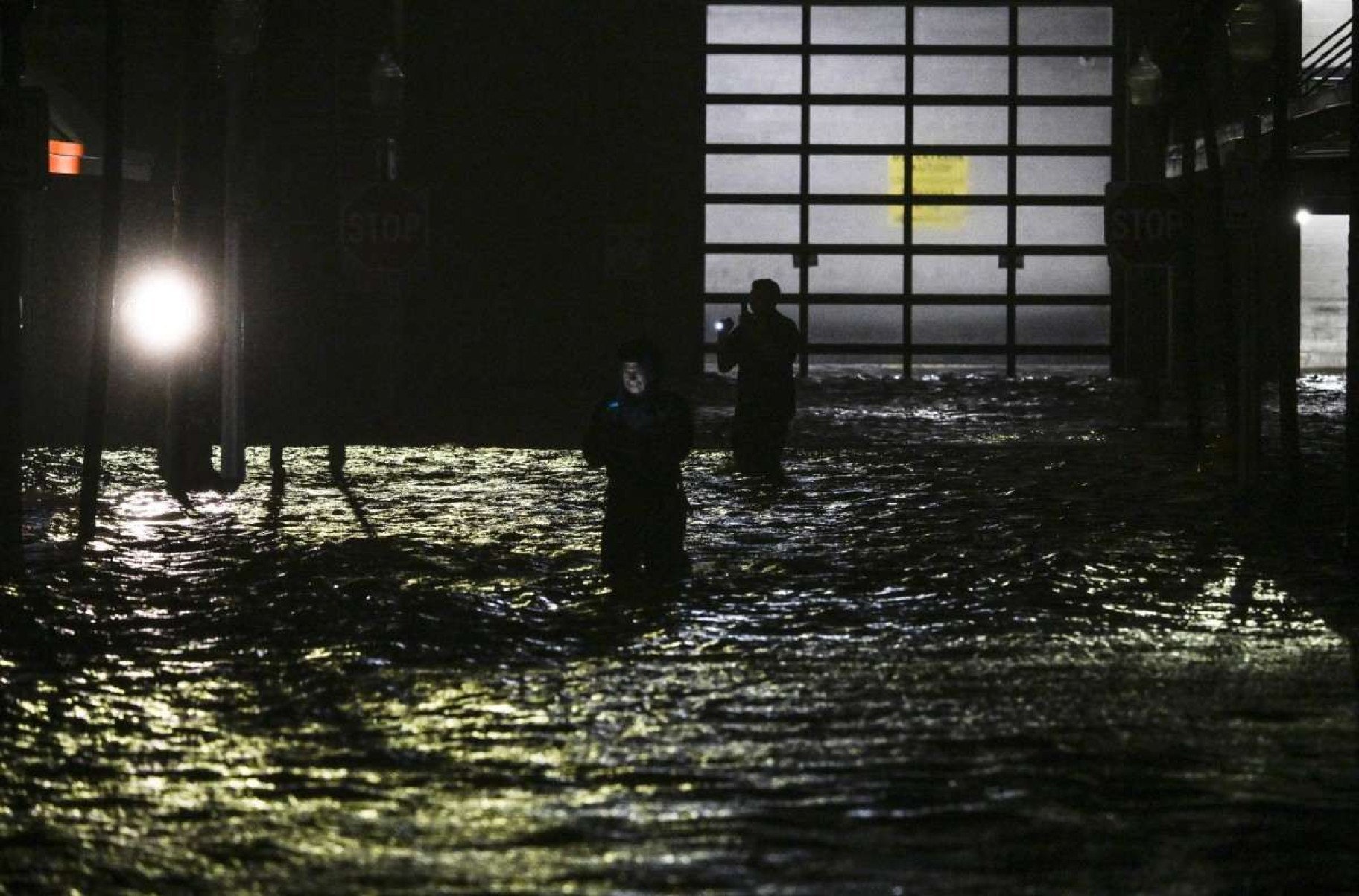 Pessoas tiram fotos e gravam vídeos enquanto caminham pelas ruas inundadas pelas enchentes depois que o furacão Milton atingiu Fort Myers, Flórida, em 9 de outubro de 2024 