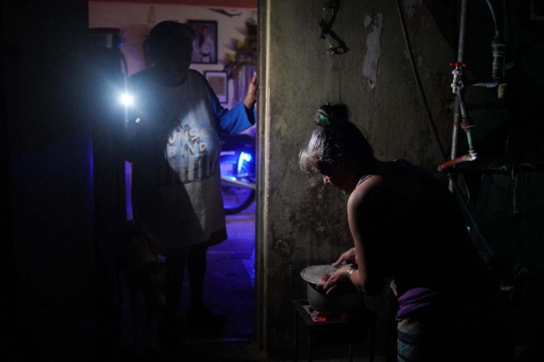  A woman boils water while another lights her with a mobile phone during a nationwide blackout caused by a grid failure in Matanzas, Cuba, on October 18, 2024. Technical breakdowns, fuel shortages and high demand have caused the countrys thermoelectric power plants to constantly fail, forcing the government to declare an energy emergency and take measures such as closing schools and factories. (Photo by Antonio LEVI / AFP)       