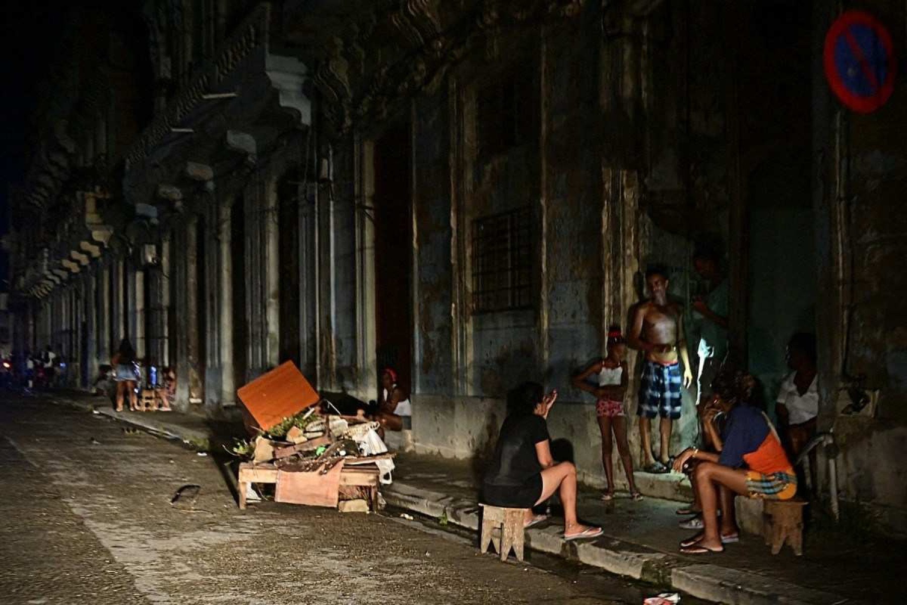  Cubans chat at night on a street during a nationwide blackout caused by a grid failure in Havana on October 18, 2024. Technical breakdowns, fuel shortages and high demand have caused the countrys thermoelectric power plants to constantly fail, forcing the government to declare an energy emergency and take measures such as closing schools and factories. (Photo by Adalberto ROQUE / AFP)       