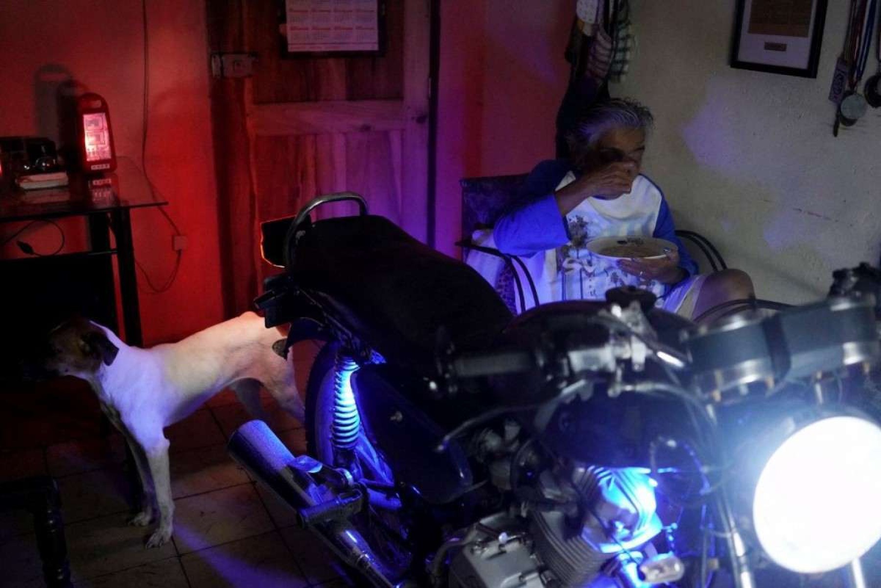     Uma mulher come em sua casa ao lado de uma motocicleta que lhe fornece eletricidade durante um apagão nacional causado por uma falha na rede em Matanzas, Cuba, em 18 de outubro de 2024. Avarias técnicas, escassez de combustível e alta demanda causaram o colapso das usinas termelétricas do país. falham constantemente, forçando o governo a declarar uma emergência energética e a tomar medidas como o fechamento de escolas e fábricas. (Foto de Antonio LEVI/AFP)       