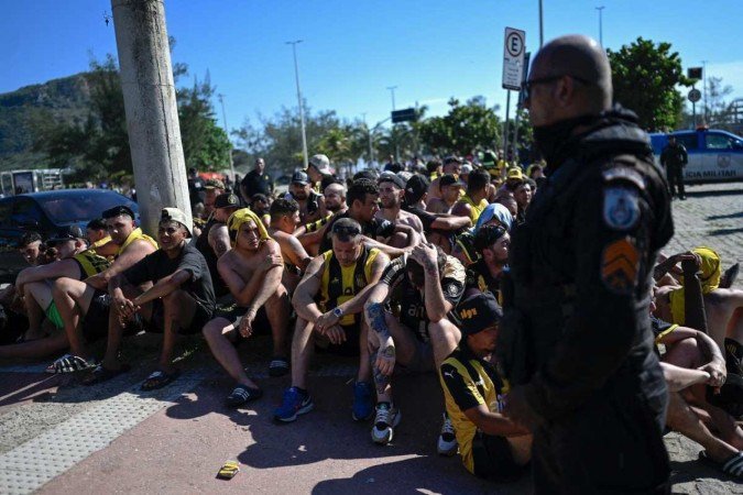Torcedores do Peñarol incendeiam ônibus e moto, depredam quiosque, e entram em confronto com a polícia no Recreio -  (crédito: Mauro Pimentel/AFP)