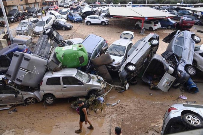 Wreckage of cars and debris are piled up in the streets of Paiporta, on October 31, 2024, covered in mud after flash floods ravaged this area of Valencia region, eastern Spain. Rescuers raced on October 31, 2024 to find survivors and victims of once-in-a-generation floods in Spain that killed at least 95 people and left towns submerged in a muddy deluge with overturned cars scattered in the streets. About 1,000 troops joined police and firefighters in the grim search for bodies in the Valencia region as Spain started three days of mourning. Up to a year's rain fell in a few hours on the eastern city of Valencia and surrounding region on October 29 sending torrents of water and mud through towns and cities.  -  (crédito: Jose Jordan/AFP)