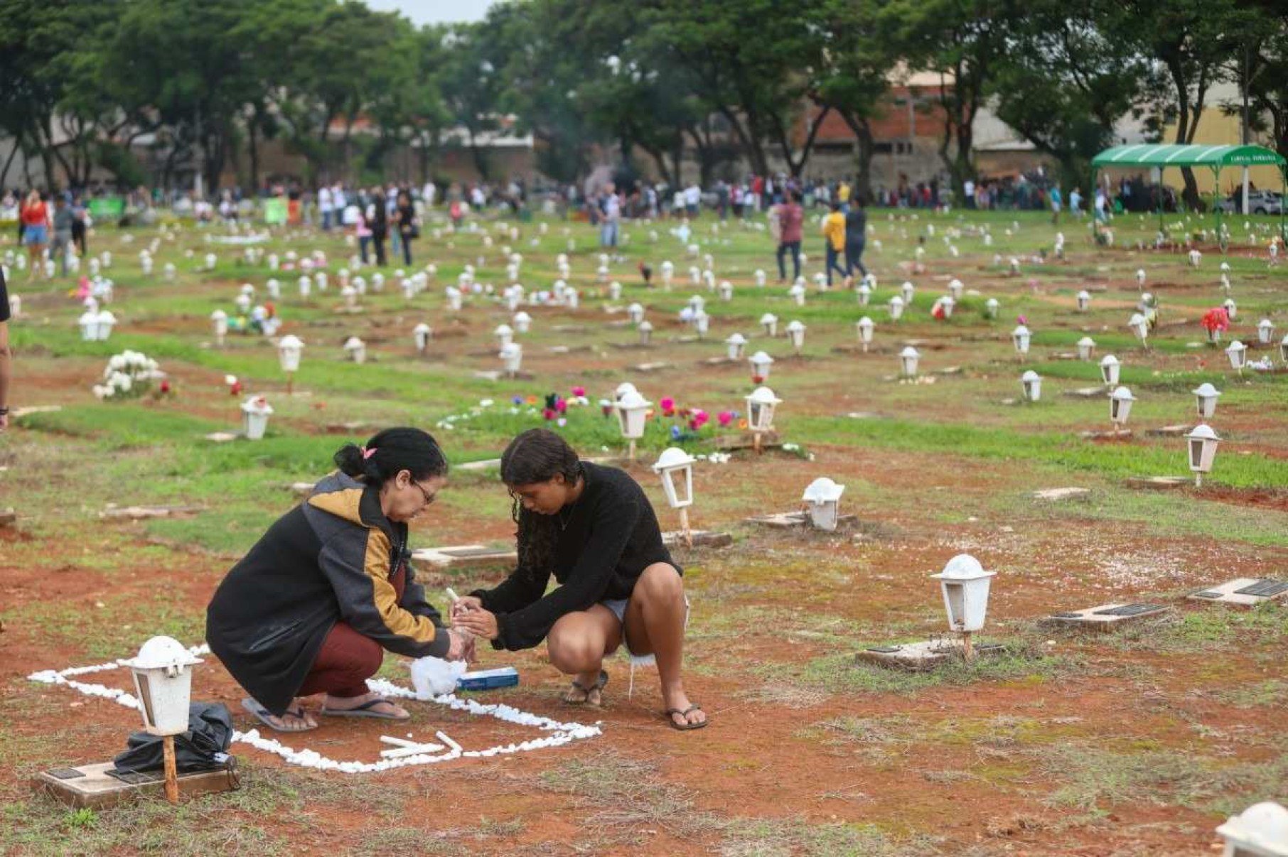 Maria Valdeni da Silva foi ao cemitério com a neta Yasmim. Elas enfeitaram o túmulo dos familiares com pedras e colocaram velas