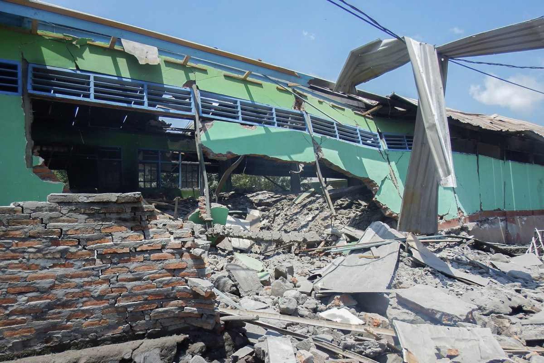  A collapsed building is seen in Klatanlo village, in East Flores Regency, East Nusa Tenggara, on November 4, 2024, in the aftermath of Mount Lewotobi Laki-Lakis eruption overnight. At least six people died after a volcano in eastern Indonesia erupted several times overnight, officials said on November 4, raising the alert level to the highest of a four-tiered system. (Photo by ARNOLD WELIANTO / AFP)       Caption 