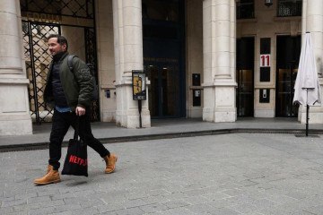 Pedestre passeia com uma bolsa da Netflix enquanto agentes cumprem mandado de busca e apreensão no escritório da empresa, em Paris -  (crédito: Ian LANGSDON / AFP)