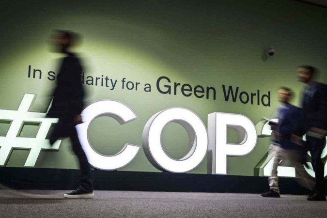  People walk past the logotype at the venue for the 2024 United Nations Climate Change Conference (COP29) in Baku on November 11, 2024. The COP29 climate talks open on November 11 in Azerbaijan, under the long shadow cast by the re-election of Donald Trump, who has pledged to row back on the United States' carbon-cutting commitments. (Photo by Alexander NEMENOV / AFP)
       -  (crédito:  AFP)