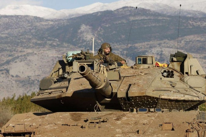 Um soldado israelense sentado em um tanque estacionado perto da fronteira na Alta Galiléia 