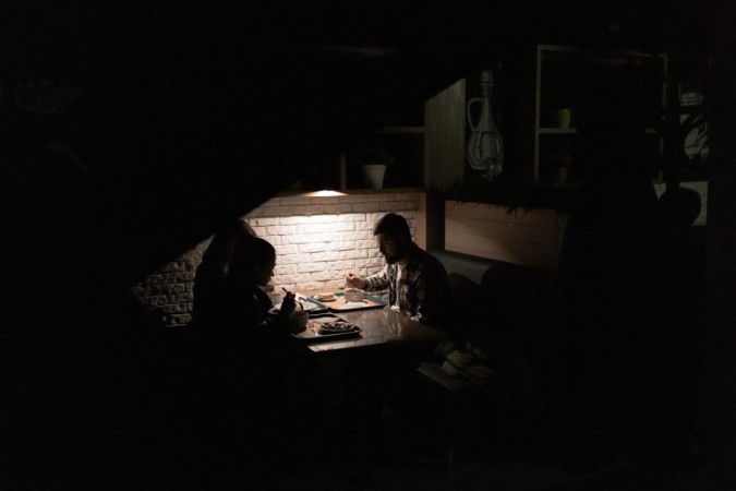 Clientes comem em restaurante afetado pela falta de eletricidade, em Kiev: 1 milhão de ucranianos sem luz  -  (crédito: Roman Pilipey/AFP)