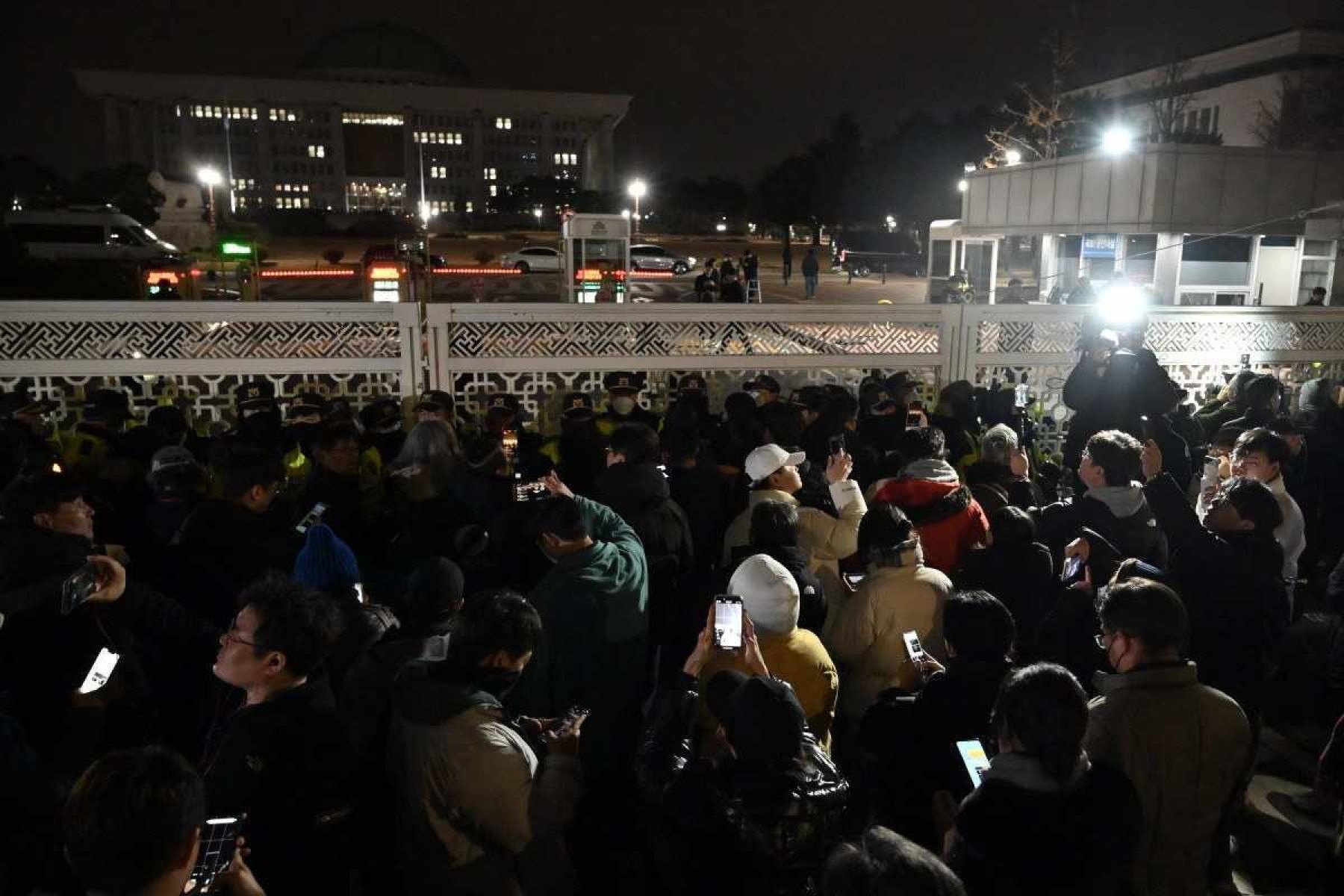  People gather in front of the main gate of the National Assembly in Seoul, South Korea on December 4, 2024, after President Yoon Suk Yeol declared emergency martial law. South Koreas President Yoon Suk Yeol on December 3 declared emergency martial law, saying the step was necessary to protect the country from 