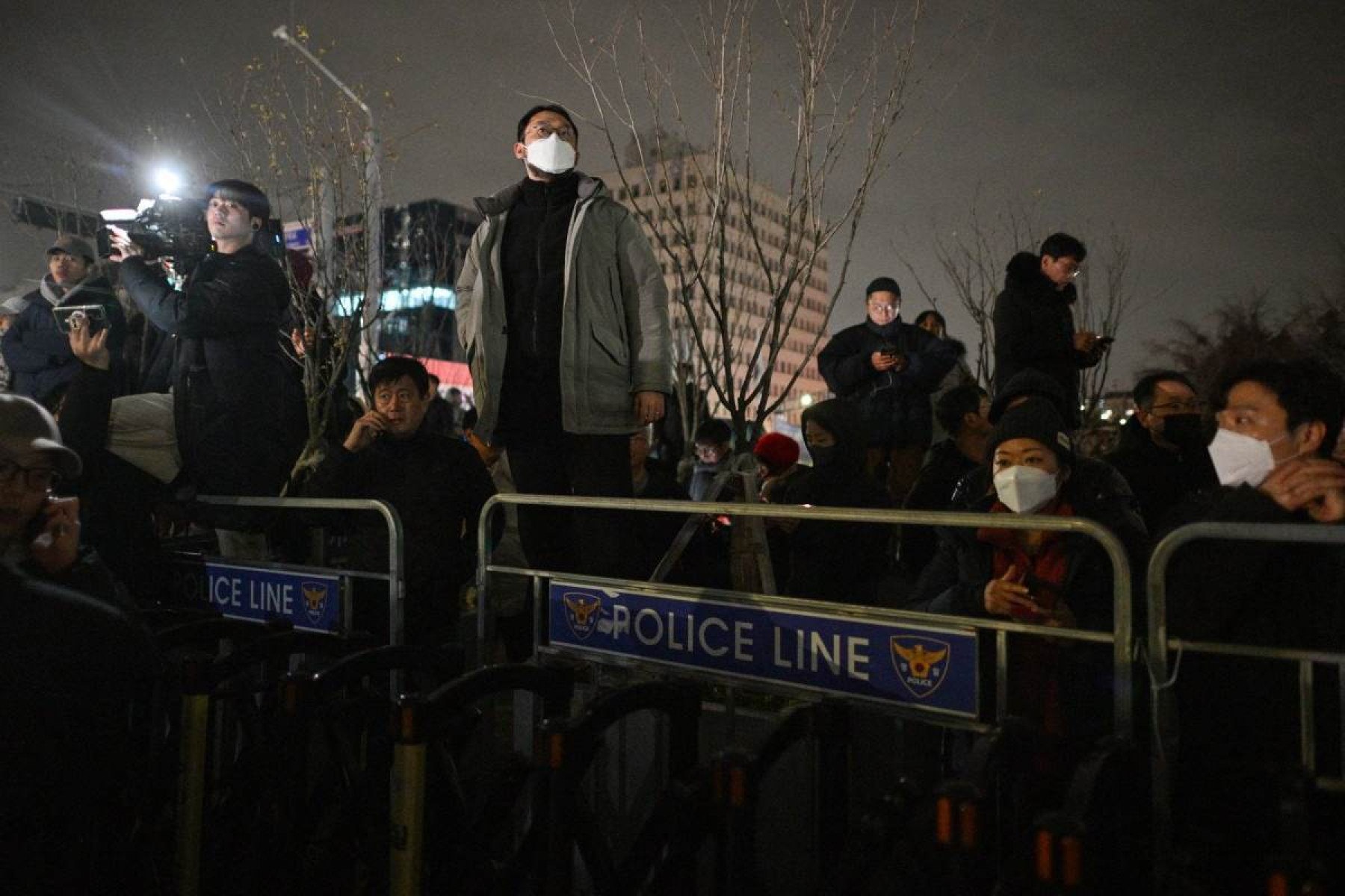  A man looks out from behind a police line outside the National Assembly in Seoul on December 4, 2024, after South Korea President Yoon Suk Yeol declared emergency martial law. South Koreas President Yoon Suk Yeol on December 3 declared emergency martial law, saying the step was necessary to protect the country from 