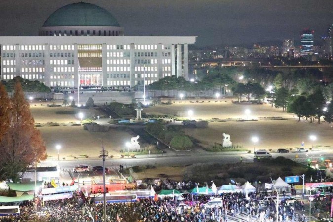 Pessoas se reúnem em frente à Assembleia Nacional em Seul em 4 de dezembro de 2024, depois que o presidente da Coreia do Sul, Yoon Suk Yeol, declarou a lei marcial -  (crédito: YONHAP / AFP)