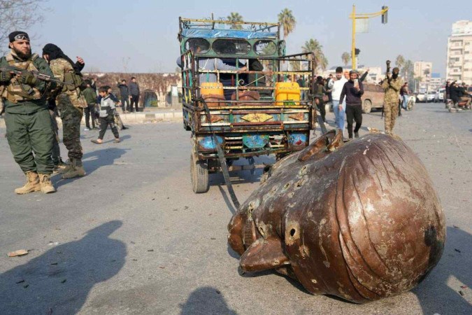 Caminhão puxa parte da cabeça da estátua do ex-presidente Hafez Al-Assad, pai do atual ditador Bashar Al-Assad, em Hama (centro-oeste) -  (crédito: Muhammad Haj Kadour/AFP)