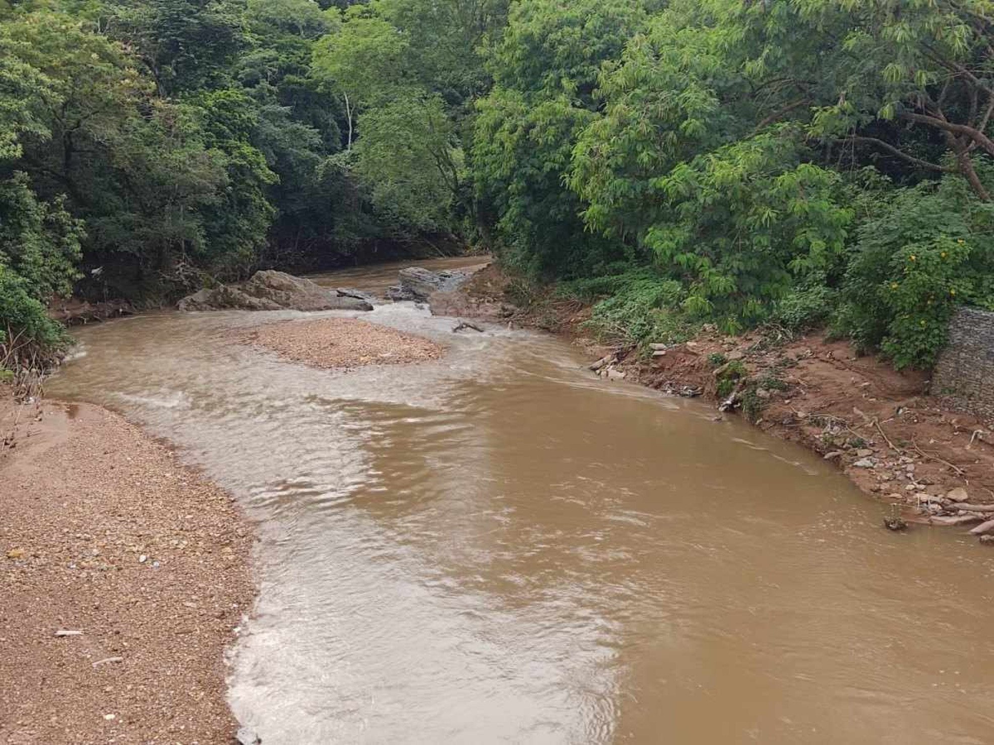 Trecho do Rio Melchior com água turva e lixo na margem