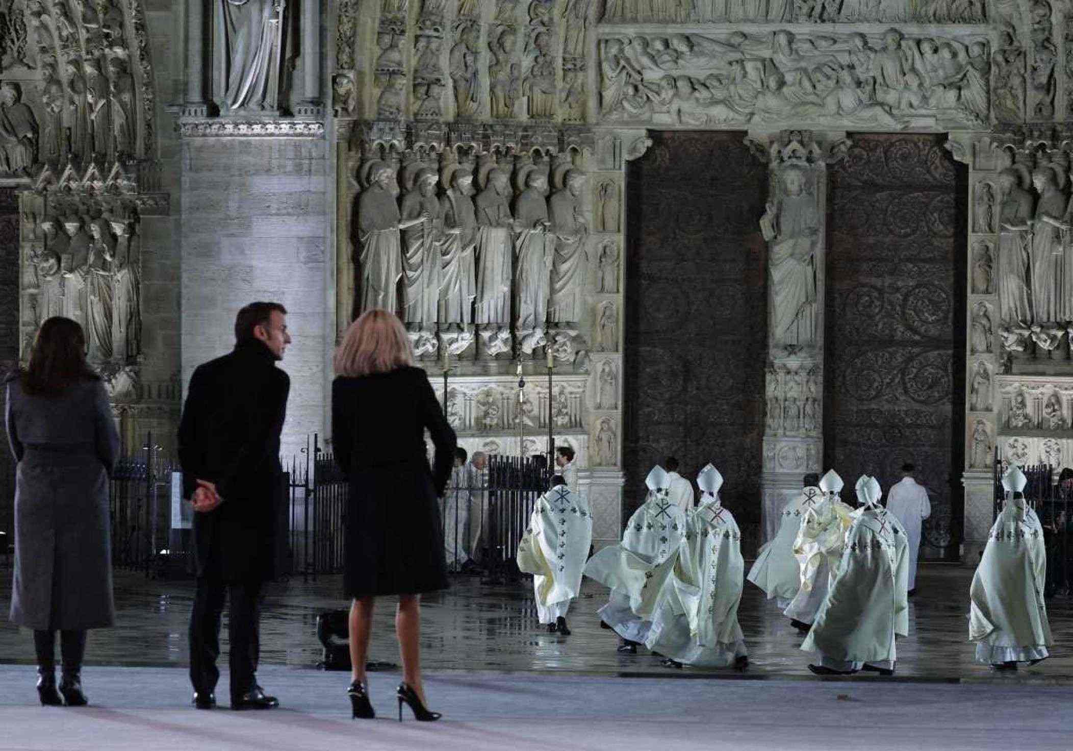 A prefeita de Paris, Anne Hidalgo (E), o presidente francês Emmanuel Macron (2E) e sua esposa Brigitte Macron (3D) estão de pé enquanto o arcebispo de Paris, Laurent Ulrich, lidera o clero em direção às portas da Catedral de Notre-Dame durante uma cerimônia para marcar a reabertura da catedral histórica, no centro de Paris, em 7 de dezembro de 2024. Cerca de 50 chefes de estado e de governo são esperados na capital francesa para comparecer à cerimônia que marca a reconstrução da obra-prima gótica cinco anos após o incêndio de 2019 que devastou o marco do patrimônio mundial e derrubou sua torre. Cerca de 250 empresas e centenas de especialistas fizeram parte do projeto de restauração de cinco anos a um custo de centenas de milhões de euros. (Foto de Christophe PETIT TESSON / POOL / AFP)