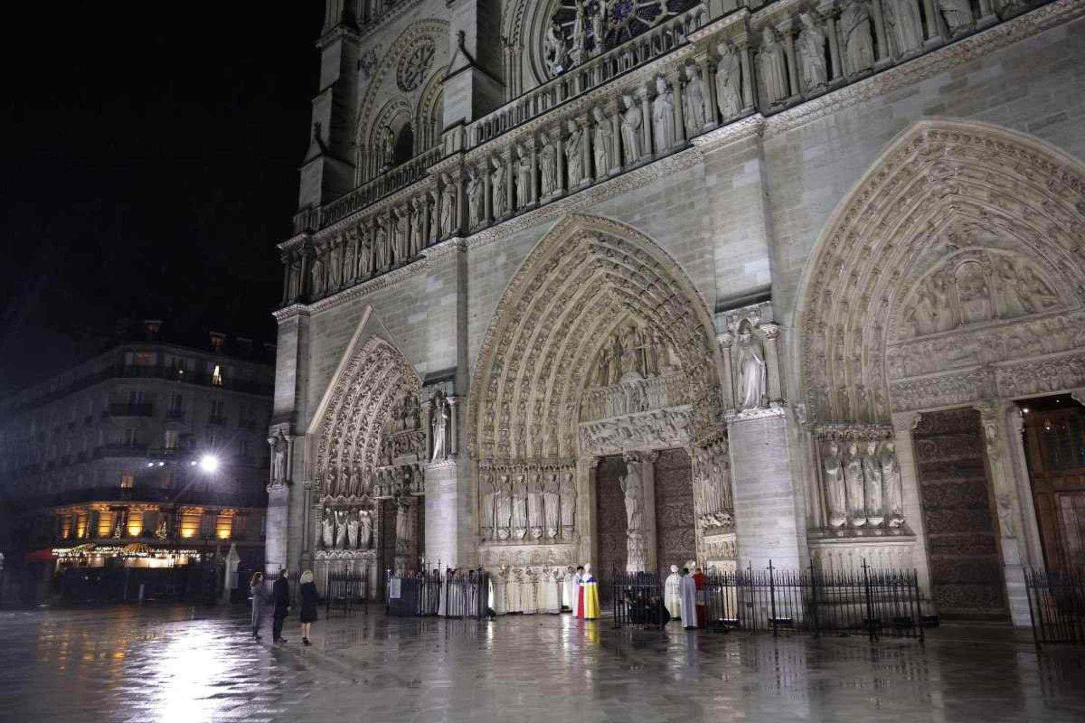 A prefeita de Paris, Anne Hidalgo (E), o presidente francês Emmanuel Macron (2E) e sua esposa Brigitte Macron (3D) estão de pé enquanto o arcebispo de Paris, Laurent Ulrich, lê em frente às portas da Catedral de Notre-Dame durante uma cerimônia para marcar a reabertura da catedral histórica, no centro de Paris, em 7 de dezembro de 2024. Cerca de 50 chefes de estado e de governo são esperados na capital francesa para comparecer à cerimônia que marca a reconstrução da obra-prima gótica cinco anos após o incêndio de 2019 que devastou o marco do patrimônio mundial e derrubou sua torre. Cerca de 250 empresas e centenas de especialistas fizeram parte do projeto de restauração de cinco anos a um custo de centenas de milhões de euros. (Foto de Christophe PETIT TESSON / POOL / AFP)