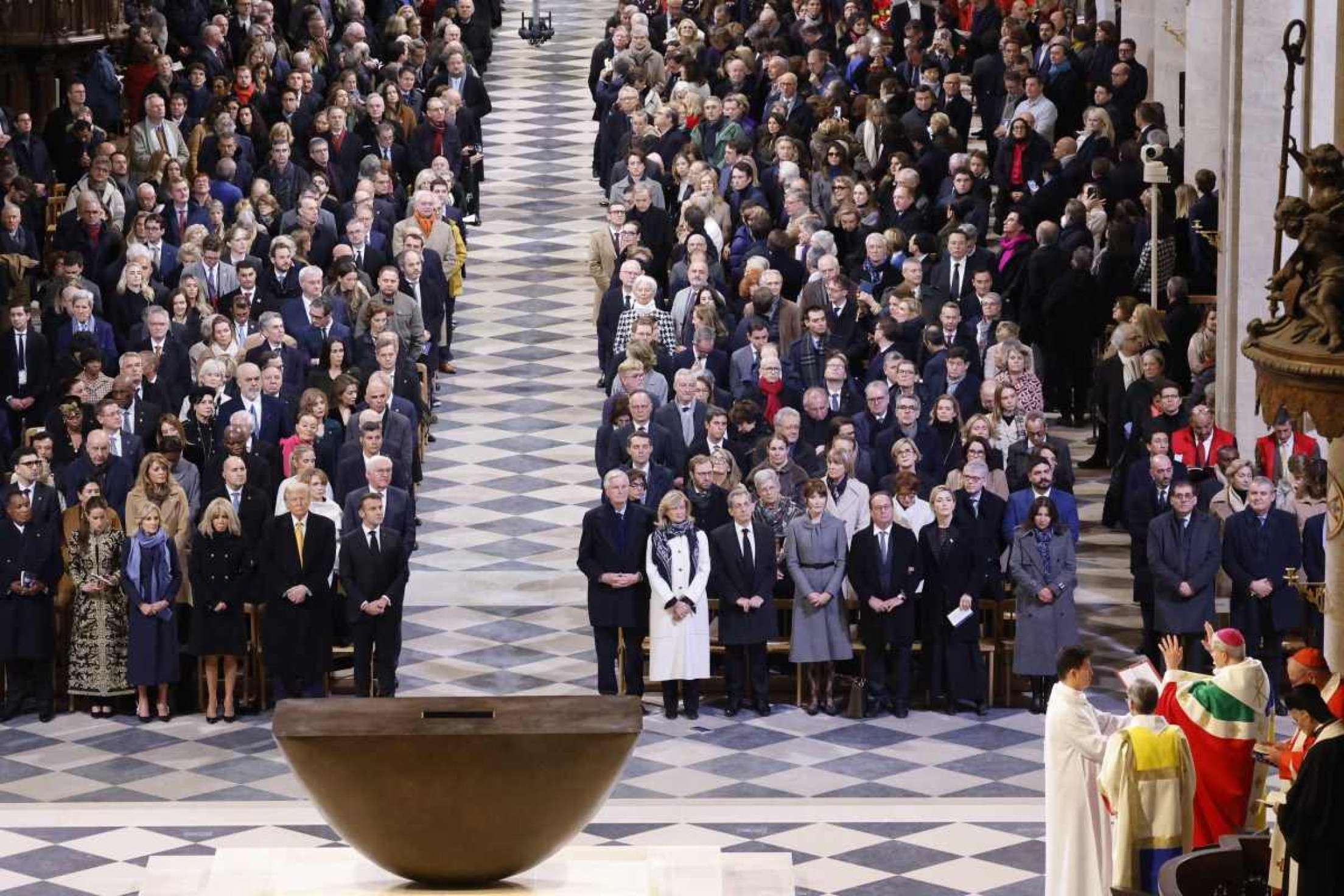 Líderes mundiais, políticos e convidados se levantam enquanto o Arcebispo de Paris Laurent Ulrich (D) lê durante uma cerimônia para marcar a reabertura da histórica Catedral de Notre-Dame, no centro de Paris, em 7 de dezembro de 2024. Cerca de 50 chefes de estado e governo são esperados na capital francesa para comparecer à cerimônia que marca a reconstrução da obra-prima gótica cinco anos após o incêndio de 2019 que devastou o marco do patrimônio mundial e derrubou sua torre. Cerca de 250 empresas e centenas de especialistas fizeram parte do projeto de restauração de cinco anos a um custo de centenas de milhões de euros. (Foto de Ludovic MARIN / POOL / AFP)