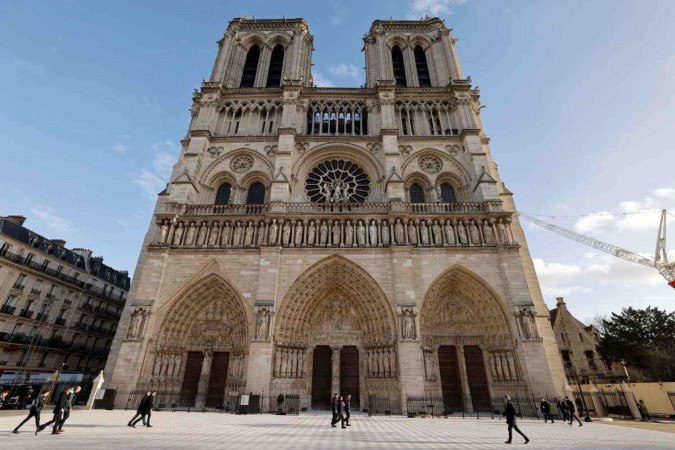 Pessoas caminham em frente à Catedral de Notre-Dame de Paris, antes de sua cerimônia oficial de reabertura, após mais de cinco anos de trabalhos de reconstrução       -  (crédito: LUDOVIC MARIN / POOL / AFP)