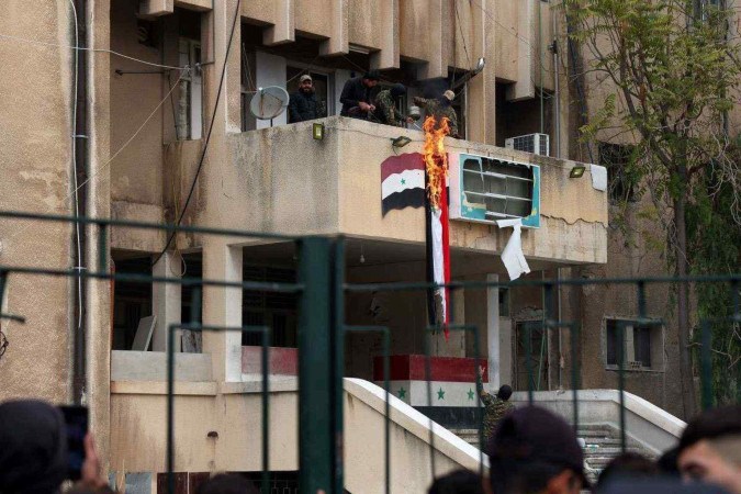  Forças antigovernamentais atearam fogo à bandeira síria na cidade de Salamiyah, na província central de Hama, em 7 de dezembro de 2024. Forças rebeldes pressionando uma ofensiva relâmpago na Síria visam derrubar o governo do presidente Bashar al-Assad, disse seu líder islâmico em uma entrevista publicada em 6 de dezembro. Em pouco mais de uma semana, a ofensiva viu a segunda maior cidade da Síria, Aleppo, e a estrategicamente localizada Hama caírem do controle de Assad pela primeira vez desde que a guerra civil começou em 2011. (Foto de Omar HAJ KADOUR / AFP) -  (crédito: Omar HAJ KADOUR / AFP)