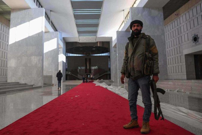     combatentes caminham no palácio presidencial sírio em Damasco em 8 de dezembro de 2024, depois que rebeldes liderados por islâmicos declararam que tomaram a capital síria em uma ofensiva relâmpago, fazendo com que o presidente Bashar al-Assad fugisse e pondo fim a cinco décadas de governo do Baath na Síria. (Foto de OMAR HAJ KADOUR/AFP)
      