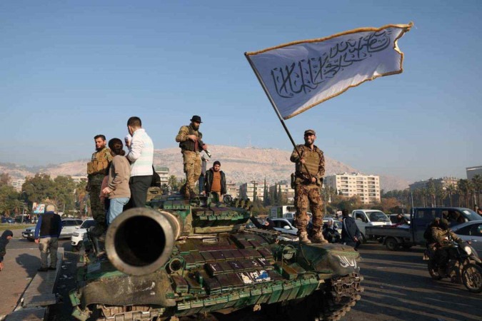 Combatente da oposição ostenta bandeira islâmica sobre tanque, em Damasco: grupo Hayat Tahrir al Sham (HTS) tinha elos com a Al-Qaeda -  (crédito: Omar Haj Kadour/AFP)